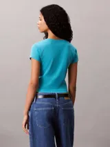 Remera de Calvin Klein confeccionada en punto de algodón elástico con textura de canalé fino. Presenta un diseño de corte slim, cuello en V, manga corta y una insignia con el logo de la marca en el pecho.