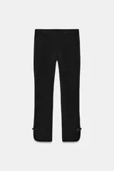 Pantalón capri negro de tiro medio con cintura elástica y detalle de alamares en el bajo.