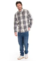Camisa de manga larga con estampado a cuadros en tonos beige, gris y negro. Presenta cuello clásico, cierre frontal con botones y un bolsillo en el pecho con el logo de la marca.