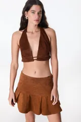 Top corto marrón de cuero con escote halter y espalda descubierta.