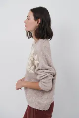Buzo de tejido de punto en color beige, con cuello redondo y mangas largas. Presenta un delicado bordado de ramas y hojas en color crema en la parte superior del frente.