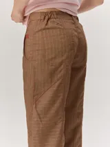 Pantalón de lino color blanco crudo, de corte barrel, con bolsillos laterales y costuras pespunteadas a contratono.