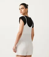 Enterito corto de tirantes finos ajustables, color blanco con rayas verticales finas, escote en V y bolsillos delanteros.