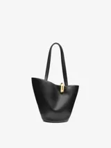 Bolso tipo tote asimétrico de cuero liso color negro, con diseño de cubo, doble asa superior y cierre de anilla metálica dorada. Incluye logo de la marca en letras doradas en la parte inferior.