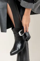 Bota corta de cuero color chocolate, con taco cuadrado y hebilla metálica decorativa en el lateral. Presenta un diseño clásico con punta redondeada.