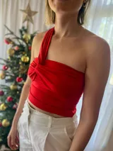 Top asimétrico de lycra color rojo, con diseño de un solo hombro y detalle de nudo frontal. Presenta un calce ajustado al cuerpo.