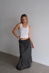 Pollera larga negra con estampado de lunares blancos, tiro alto con elástico y cordón ajustable en la cintura.