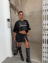 Minifalda de tiro bajo confeccionada en denim negro, con diseño plisado y detalle de hebilla frontal. Presenta un tajo lateral que aporta un estilo moderno y audaz.