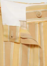 Pantalon de corte recto y tiro medio, confeccionado en tejido mezcla de lino y viscosa con diseño de rayas verticales en tonos amarillos y beige. Cuenta con cierre frontal de cremallera y botón, trabillas para cinturón y bolsillos laterales.