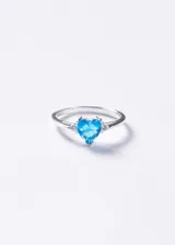 Anillo de plata 925 con piedra central de zirconia en forma de corazón color turquesa y dos pequeñas zirconias blancas a los lados.