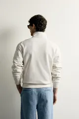 Sudadera negra de corte regular fit, con cuello subido, cierre frontal de cremallera corta y acabados en rib elástico en puños y cintura.