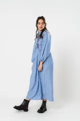 Vestido largo a rayas verticales azules y blancas, con manga globo y diseño de nido de abeja con hilo elástico hasta la cintura. Cuello alto fruncido y falda amplia con caída fluida.