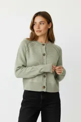 Cardigan acrílico color verde menta, de punto liso, corte al cuerpo, con cuello a la base, mangas largas con detalle trenzado y cierre frontal con botones marrones.