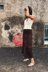 Falda midi de corte acampanado confeccionada en tejido con efecto ante color bordó. Presenta tiro medio, trabillas en la cintura y cierre frontal con cremallera y gancho metálico.