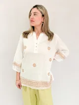 Blusa blanca de manga 3/4 con bordados en hilo verde oliva, cuello mao con abertura y botones, y terminación bordada en el ruedo y puños.