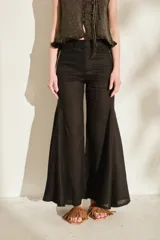 Pantalón negro de lino de tiro alto, con diseño ajustado en las caderas y perneras amplias y acampanadas con paneles insertados que generan mucho vuelo en el bajo.