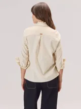 Camisa de algodón con cuello clásico y detalle de volados en la cartera delantera. Presenta mangas largas con puños abotonados y un diseño de corte recto.