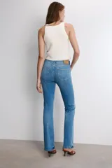 Jeans de tiro medio con corte bootcut y ajuste slim. Presenta diseño de cinco bolsillos, trabillas en la cintura y cierre frontal con cremallera y botón. Incluye detalle de pespuntes marcados a contraste.