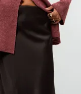 Pollera midi de corte evasé confeccionada en tejido satinado de poliéster. Presenta un diseño liso con acabado brillante, cintura estructurada y caída fluida.