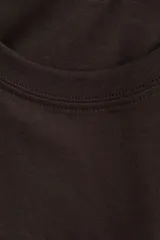 Remera marrón de corte recto con cuello redondo y mangas cortas. Estampado frontal con el texto "Madeleine PASTISSERIE & BOOK SHOP", el dibujo de un libro abierto, un croissant y la frase "buttery and flaky croissants".