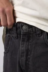 Jean baggy de corte holgado con múltiples bolsillos cargo frontales con cierre metálico. Presenta un acabado lavado, tiro medio y tiras de ajuste en la botamanga.