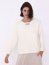 Sweater color crema de tejido de punto, con cuello redondo y prendedor de strass.