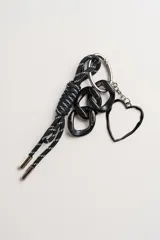 Llavero negro con cordón de nylon trenzado en blanco y negro, con dije de corazón metálico negro y eslabones de resina negra.
