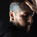 Par de aros colgantes negros con forma de daga atravesada por una cinta con la palabra 'Love' y una rosa en la parte superior.