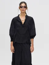 Camisa de broderie de algodón color negro, con diseño de calados, cuello mao con cierre de botones, mangas abullonadas con puños fruncidos y detalles de galones con transparencias.