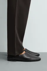 Mocasín negro de piel con parte superior lisa, horma ligeramente cuadrada y suela ultrafina.