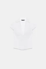 Top de popelina blanca de corte corsetero, con escote en pico pronunciado, cuello tipo solapa, mangas muy cortas y costuras marcadas.