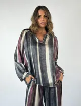 Blusa de mangas largas con cuello en V y estampado a rayas verticales en tonos gris, blanco y borgoña.