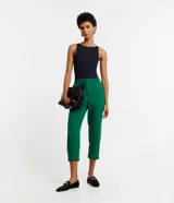 Pantalón fluido de crepé color verde, tipo pijama, de corte recto con largo tobillero. Cuenta con cintura elástica con cordón de ajuste, bolsillos laterales y cierre frontal con cremallera y botón.