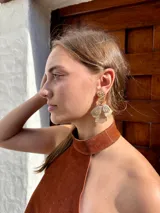 Caravanas colgantes de diseño floral con pétalos texturizados en tono dorado y detalles de pequeñas perlas en la parte superior.