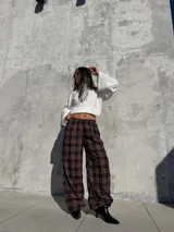 Pantalón de viyela con estampado a cuadros en tonos bordó y negro. Presenta un diseño de silueta amplia con cintura elástica y puños ajustados en los tobillos.