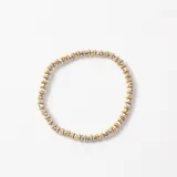 Pulsera elástica compuesta por una alternancia de pequeñas cuentas metálicas doradas y cuentas facetadas plateadas.