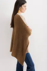 Poncho de tejido de punto con diseño oversize y aberturas laterales. Presenta un acabado con destellos brillantes y cuello redondo amplio.