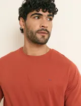 Remera básica de algodón color beige, de manga corta, con cuello redondo y un pequeño detalle bordado en el pecho.