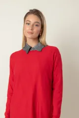 Buzo de punto fino color rojo, con cuello redondo y detalle de líneas diagonales en el mismo material.