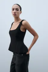 Top peplum blanco de manga sisa, con escote cuadrado y cierre de cremallera oculta en la espalda.