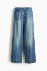 Jean de tiro alto con pierna amplia y corte holgado. Presenta cierre frontal con doble botón, bolsillos traseros de parche y pliegues marcados en el frente y la parte posterior.