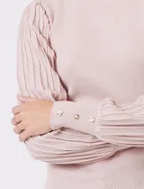 Buzo de tejido lurex marca Nanette, con cuello redondo y mangas largas con diseño plisado. Presenta puños ajustados con aplique de botones decorativos.