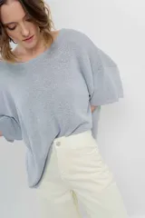 Sweater oversize de tejido liviano color blanco roto, con textura semi traslúcida, escote redondo y mangas amplias estilo murciélago.