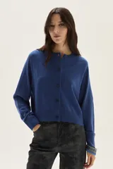 Cardigan de tejido de punto en color azul, con cuello redondo, cierre frontal con botones al tono y mangas largas con puños acanalados. Presenta un diseño clásico y versátil.