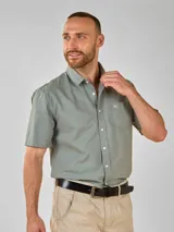 Camisa de manga corta con cuello camisero y botones frontales. El tejido es de color crema con un patrón de cuadros pequeños en negro y marrón.