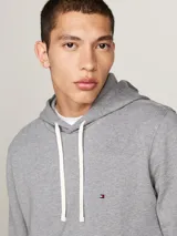 Buzo gris de felpa de algodón con capucha y cordón blanco. Tiene bolsillo tipo canguro, puños y bajo de punto canalé. Logo de Tommy Hilfiger bordado en el pecho.