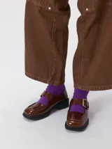 Zapatos tipo guillermina con punta cuadrada, confeccionados en lona resistente con estampado de cuadros escoceses en tonos beige, rojo y negro. Presentan una correa ajustable con hebilla metálica color bronce y una suela con taco de 4 cm.