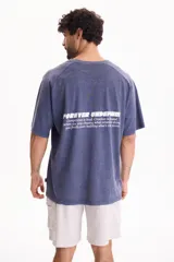 Remera de manga corta raglán con lavado acid wash color azul, de corte holgado, cuello redondo y estampa tipográfica en la espalda.