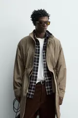 Parka relaxed fit de tejido técnico ligero, color verde militar, con cuello subido, manga larga y bolsillos de plastrón con solapa en la cadera. Cuenta con cintura ajustable con cordones y cierre frontal con cremallera oculta por solapa con botones a presión.