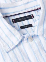 Camisa de manga corta Tommy Hilfiger, confeccionada en algodón BCI con tejido seersucker a rayas blancas y celestes. Tiene cuello clásico, cierre con botones, corte regular y logo bordado en el pecho.
